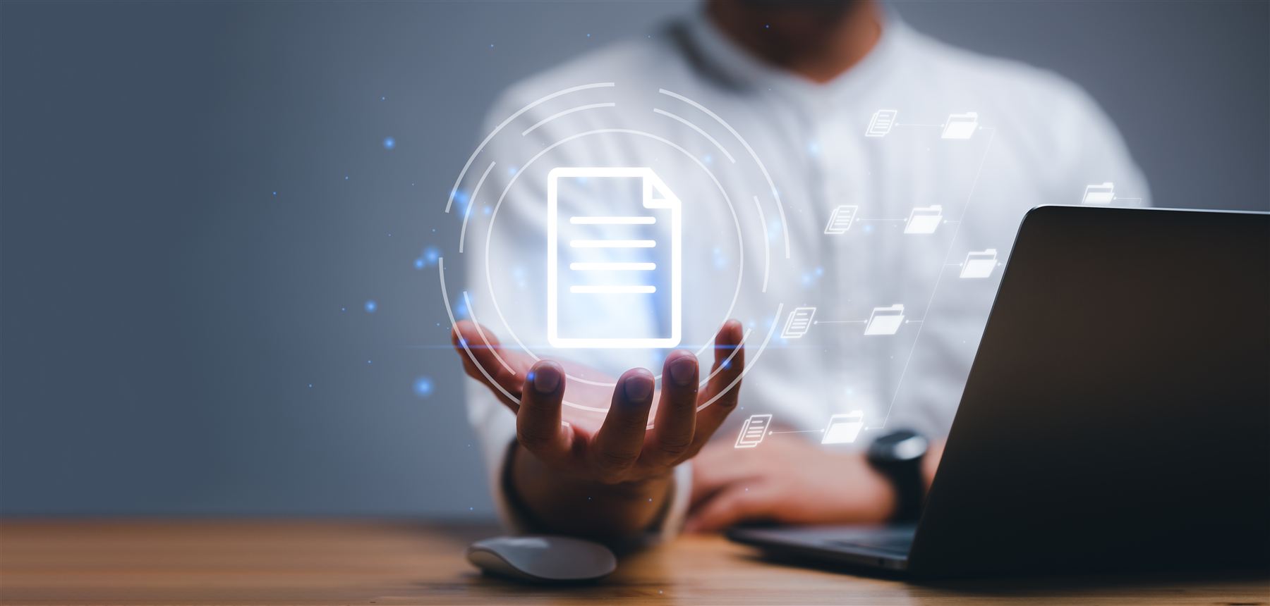 A glowing document icon held in an open hand above a laptop, as print turns digital