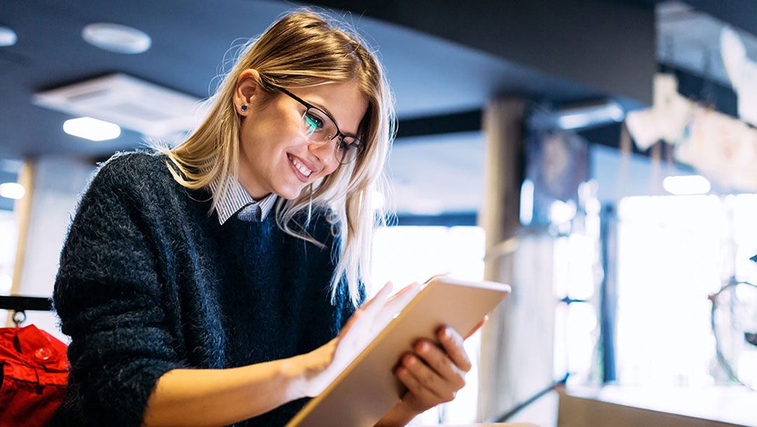 A reader smiling at a magazine on her tablet