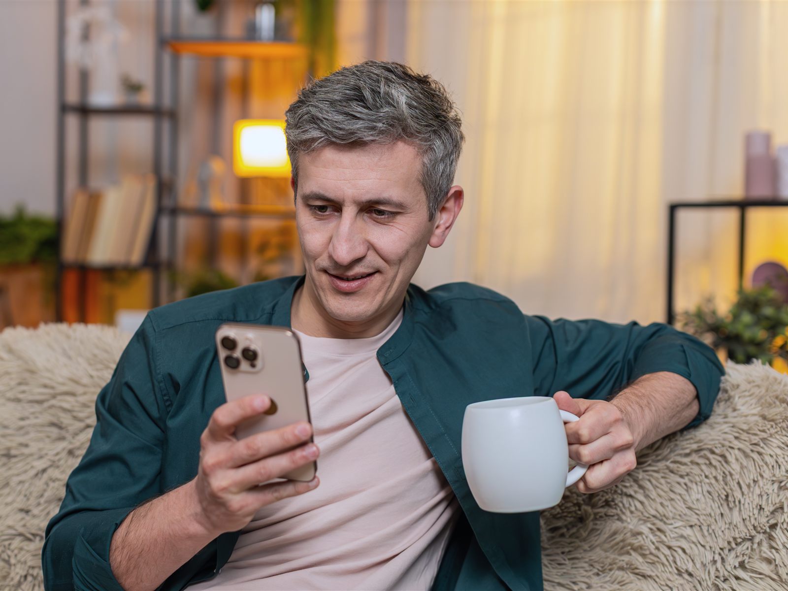 A reader on the sofa with a coffee, reading on his phone